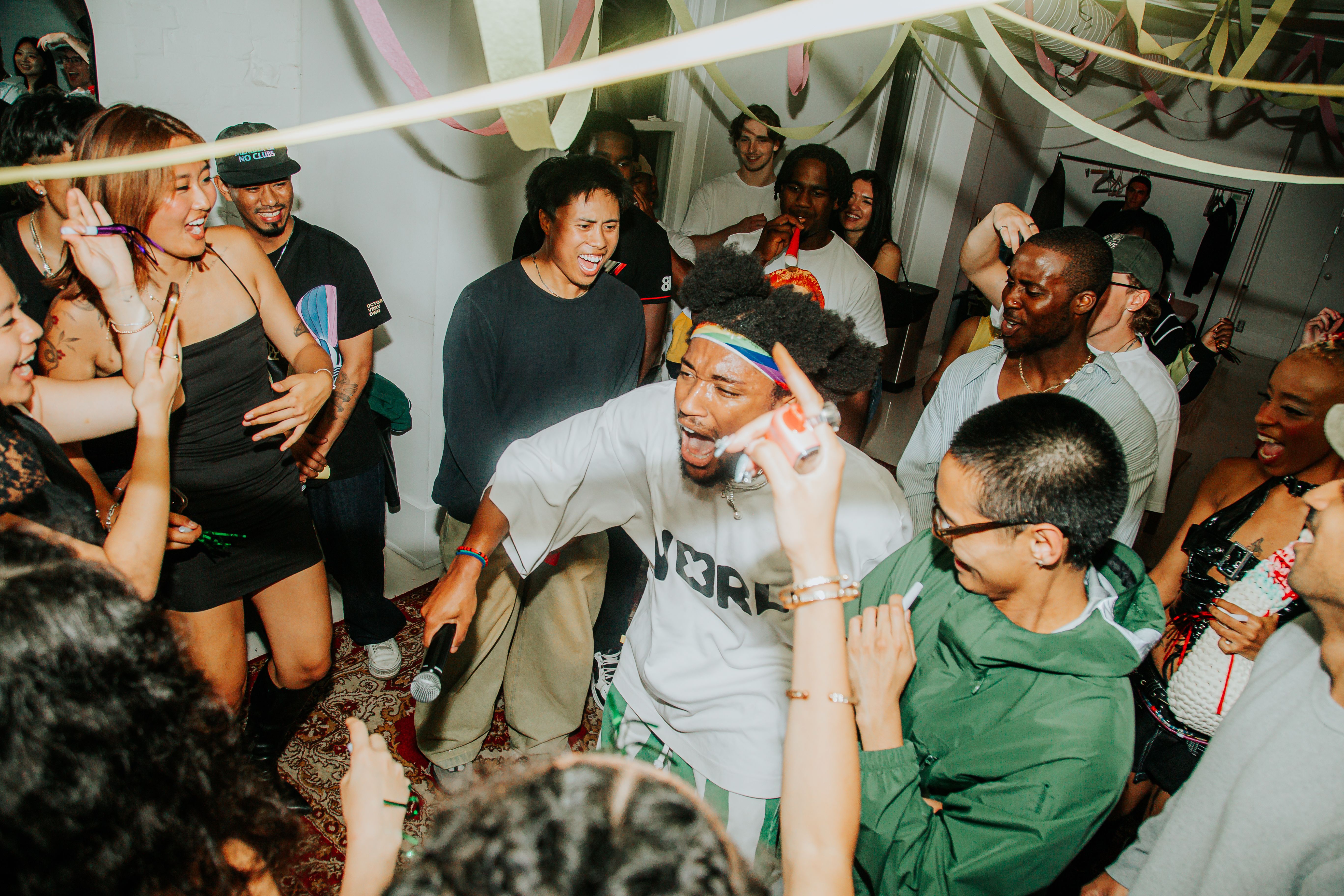 KEND! performing THE WALL! at his release party at EYE DOT STUDIOS surrounded by a crowd of people and party decorations.