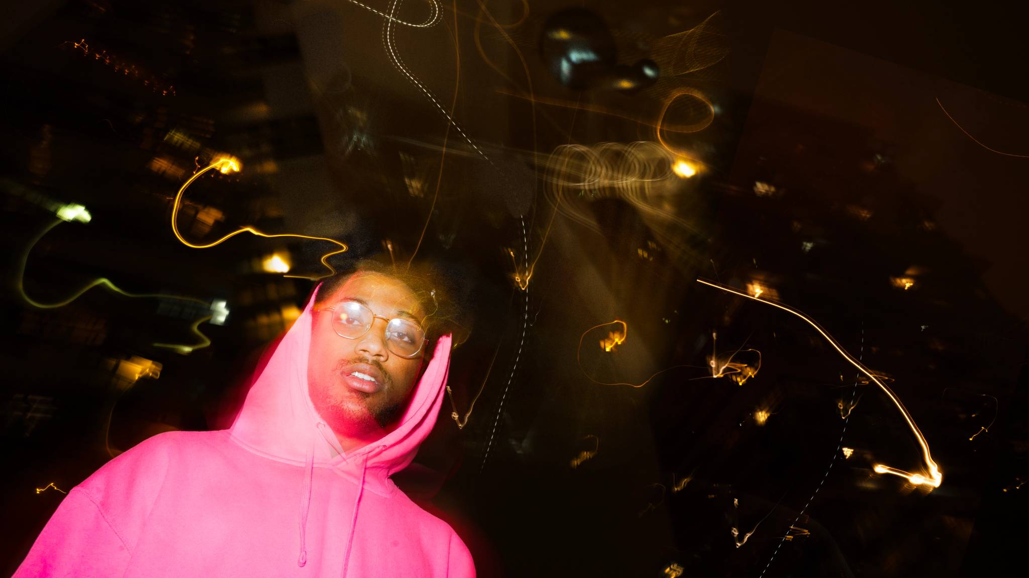 A low-exposure flash photography of KEND! wearing a pink HELLO WXRLD hoodie
